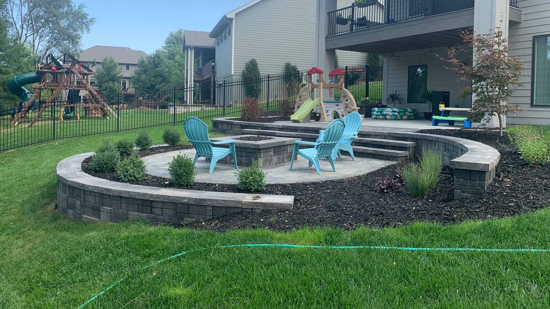 Backyard with patio and fire pit installed with landscaping done in Lincoln, NE.