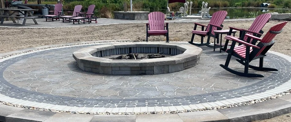 A large circular fire pit in Omaha, NE, with four red rocking chairs.