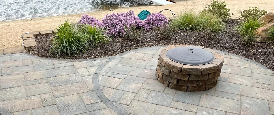Fire pit on a patio in Omaha, NE, near a landscape bed.