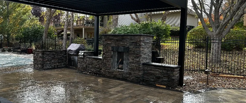 Outdoor fireplace with a fire screen in Omaha, NE, under a pergola.