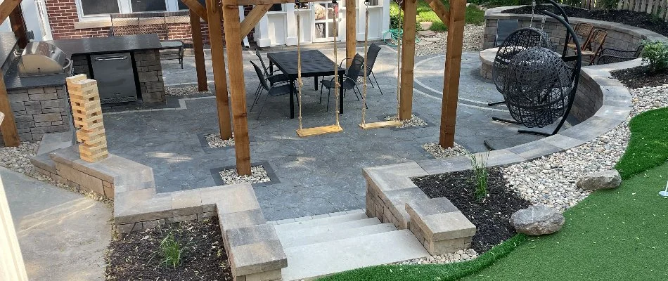 An outdoor kitchen in Omaha, NE, with a seating wall and swings.