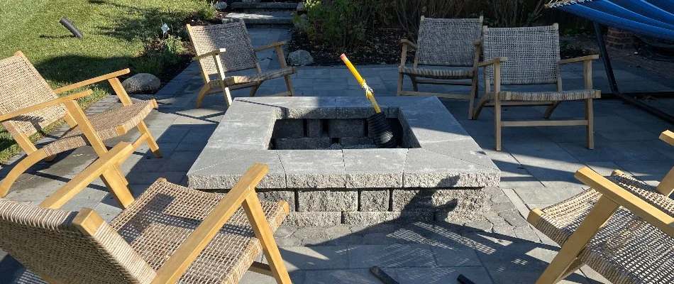 Square fire pit made of concrete block in Omaha, NE, surrounded by chairs.