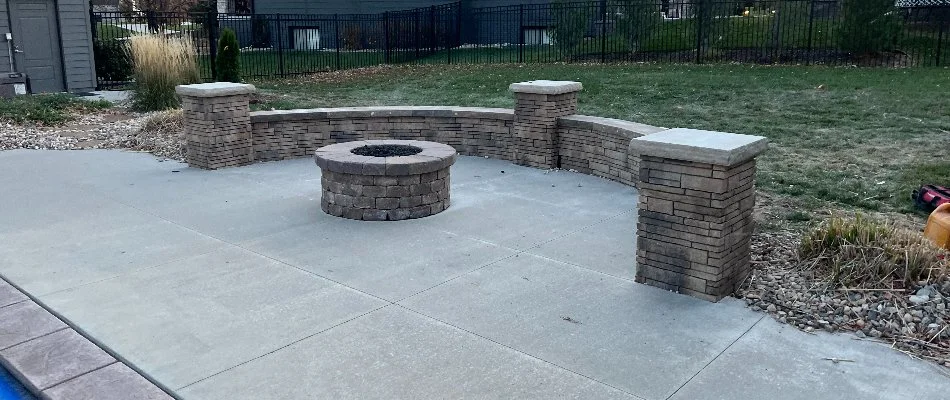 Stone seating wall around a fire pit on a concrete patio in Omaha, NE.