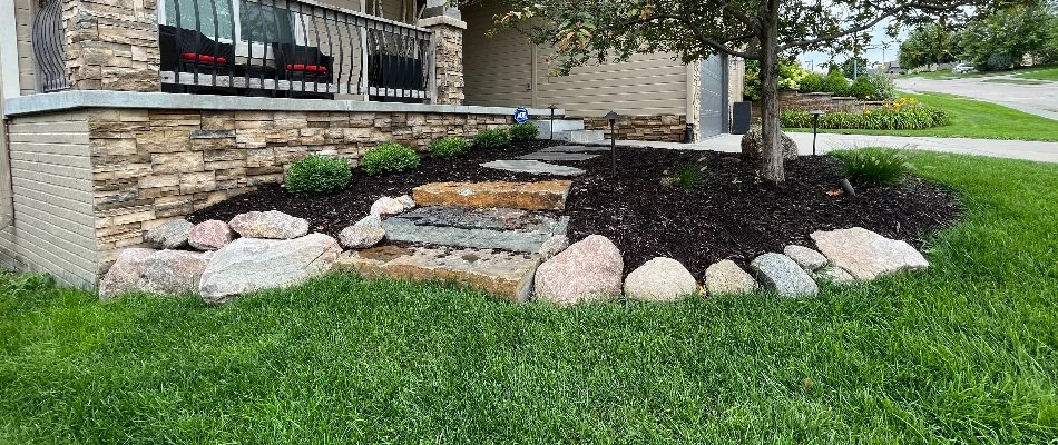 A yard in Arlington, NE, with green grass and a landscape bed with mulch ground cover.