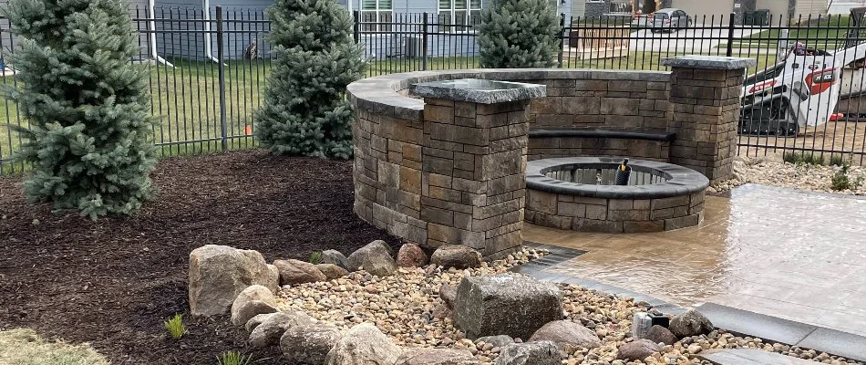 Landscape around a fire pit with seating wall in Chalco, NE.
