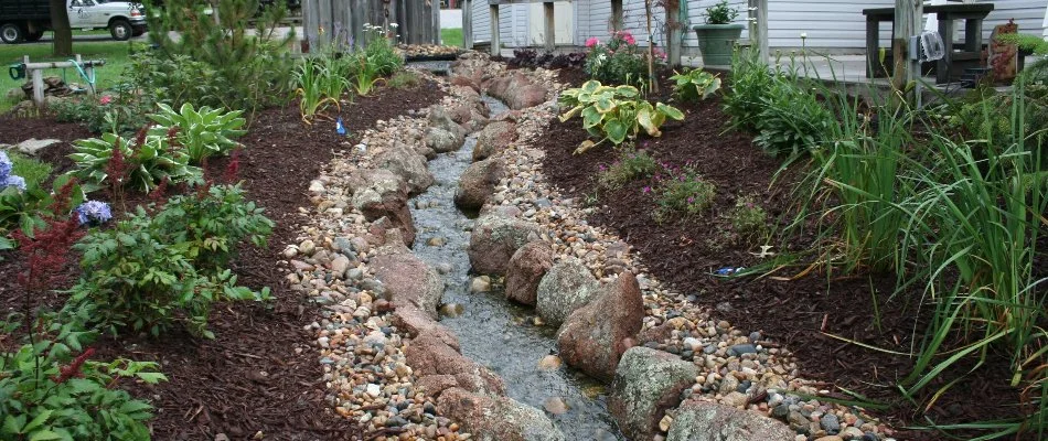 Mulched landscape in Buccaneer Bay, NE, with plants along a water feature.