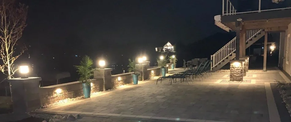 A patio area with chairs being illuminated by a landscape lighting system.