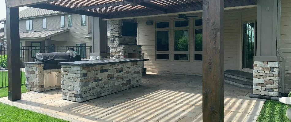Patio in Ralston, NE, with an outdoor kitchen, fireplace, and pergola.