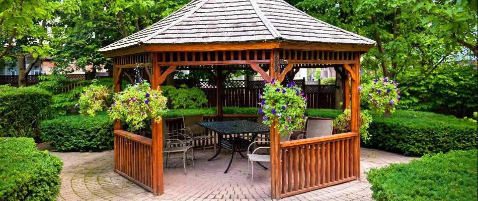 Wooden gazebo in Omaha, NE, around shrubs and plants.